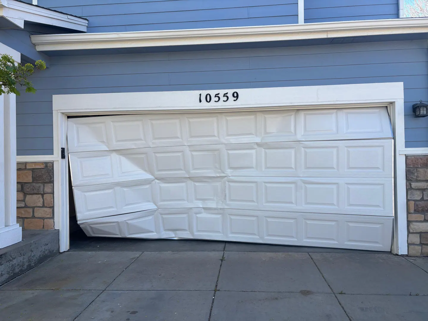 Bent white garage door jammed before repair