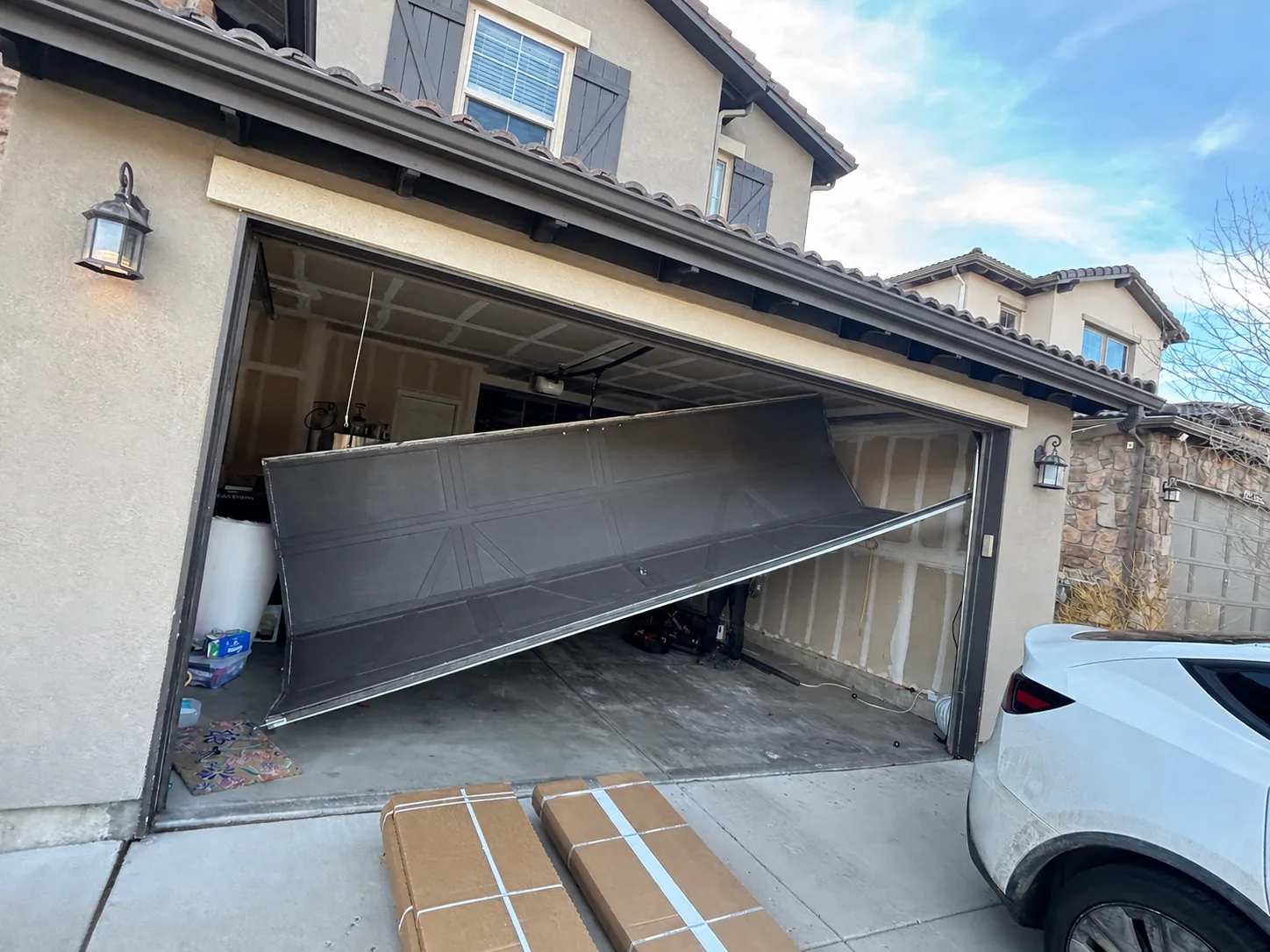 Dark garage door hanging out of the opening before replacement in the Denver area